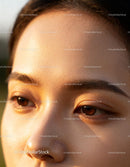 Close up of woman's natural skin and brown eyes in sunlight