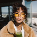 Fashionable Woman with Yellow Sunglasses and Green Smoothie on Rooftop