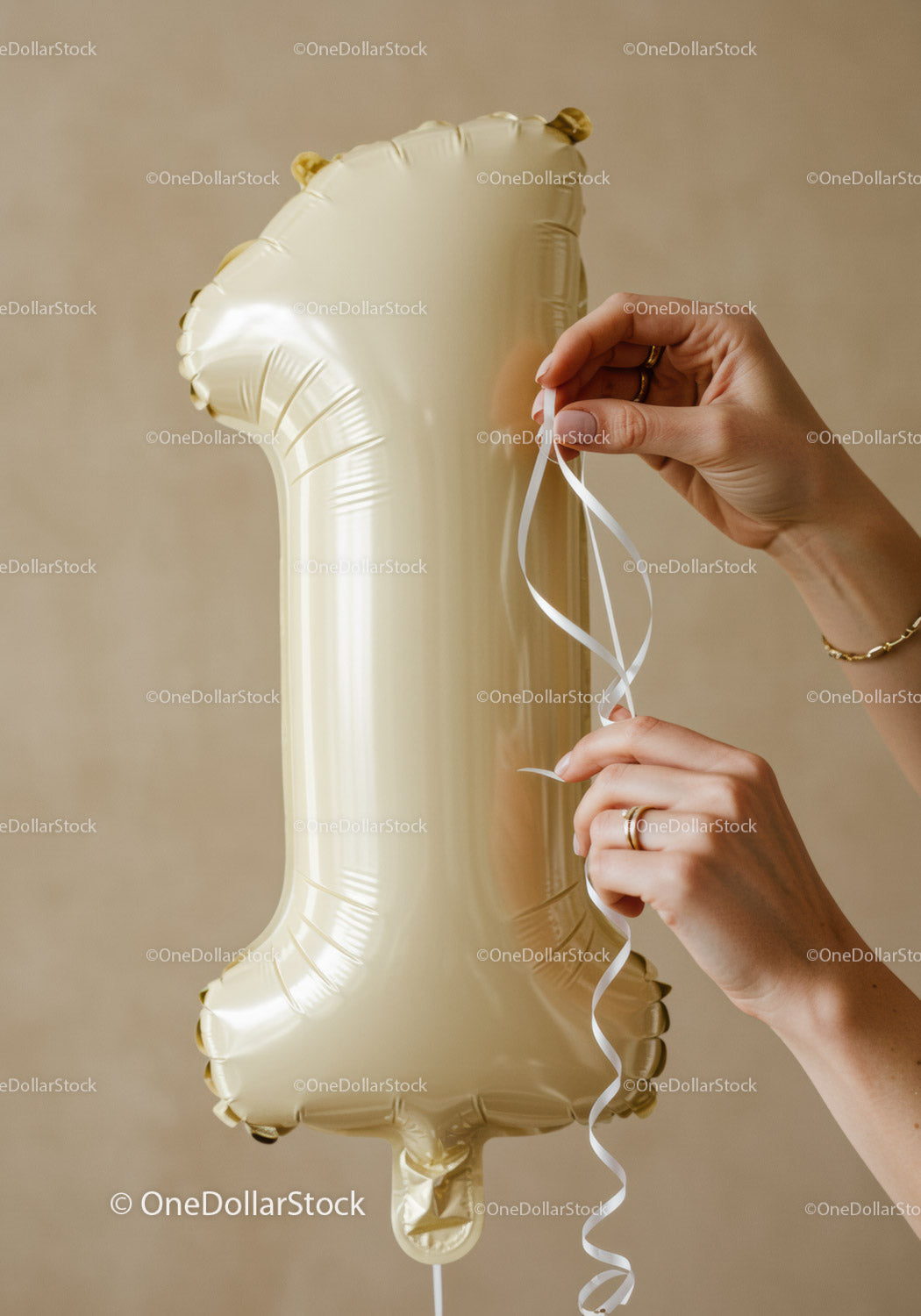 Hands tying ribbon on golden number one balloon