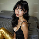 Young Woman in Black Top and Gold Pants Sitting on Bed Indoors