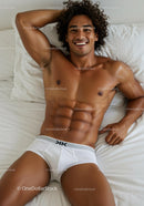Smiling young man relaxing on bed in white underwear