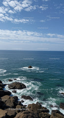 Calm Ocean with Rocky Shore and Blue Sky with Clouds