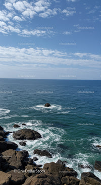 Calm Ocean with Rocky Shore and Blue Sky with Clouds
