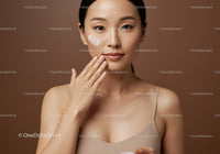 Young Woman Applying Cream with Beautiful Skin and Brown Background