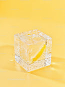 Close up of ice cube with lemon slice inside on yellow