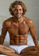 Smiling muscular man sitting on bed in white briefs