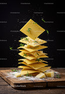 Stack of uncooked lasagna sheets with herbs and cheese
