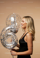 Smiling Woman Holding Number Balloons in Celebration