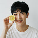 Young Man Smiling Holding Lemon Slice in Bright Studio