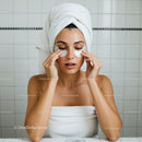 Young woman applying under eye patches in bathroom