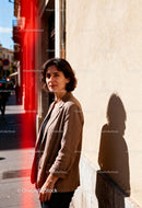 Woman standing on sunny urban street with shadow