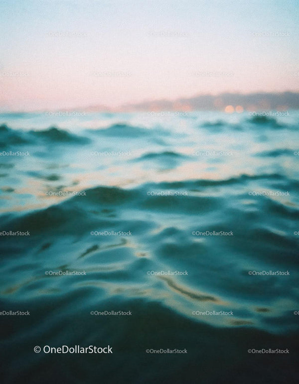 Spokojne fale oceanu pod miękkim pastelowym niebem o zachodzie słońca
