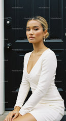 Elegant woman in white dress sitting by black door