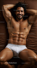 Smiling muscular man relaxing in white underwear on bed