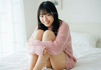 Happy Young Woman Sitting Relaxed on Bed in Cozy Pink Sweater