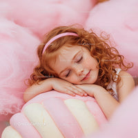 Peaceful redhead girl resting on soft pastel sweets