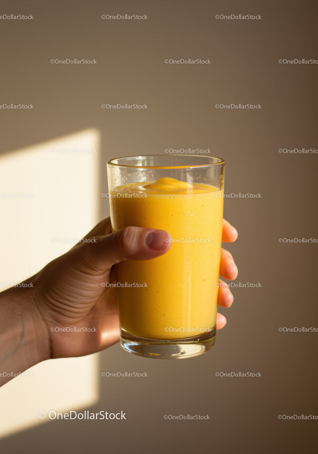 Hand Holding a Fresh Mango Smoothie in Glass
