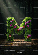 Green letter M covered with flowers in forest light