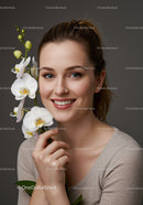 Young Woman with White Orchid Flowers in Front of Gray Background