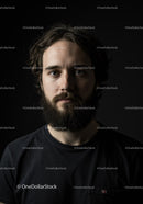 Thoughtful young man with beard against dark background
