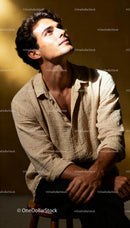 Young man sitting contemplatively in warm light