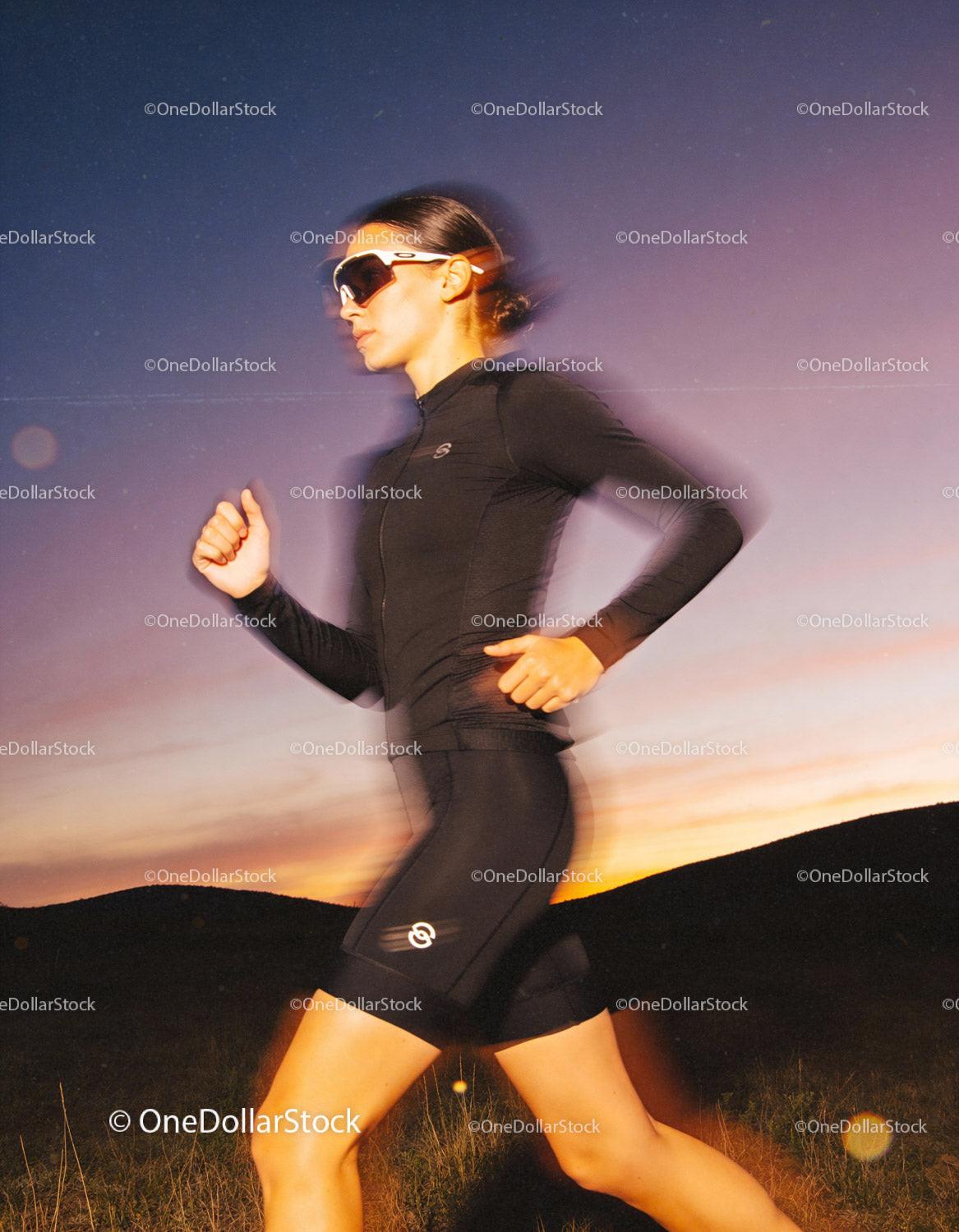 Athletic woman running outdoors at dusk in dynamic motion