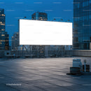 Large illuminated blank billboard on city rooftop at dusk