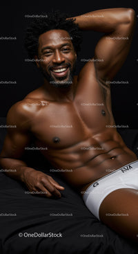 Smiling muscular man relaxing on dark bedding