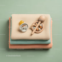 Stack of Baby Blankets with Pacifier and Wooden Rattle