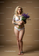 Tattooed Woman Holding Lavender Flowers in Stylish Lingerie