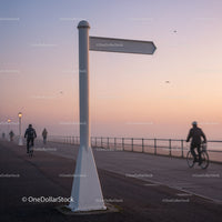 Empty directional signpost by seaside promenade at dusk