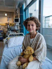 Young Boy Sitting in Hospital Bed Holding Teddy Bear in Pediatric Ward