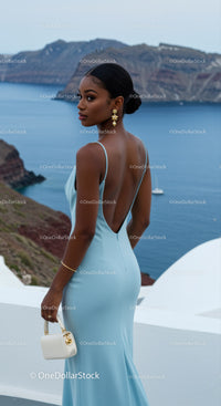 Elegant woman in blue gown overlooking sea cliffs