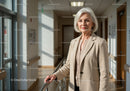 Elegant Senior Woman in Beigе Blazer Walking through Hospital Corridor
