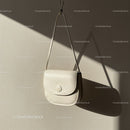 Minimalist white leather handbag hanging on wall