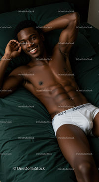 Smiling young man relaxing on dark green bed sheets