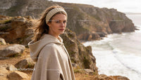 Woman wearing knitted headband and wool cape by cliffs