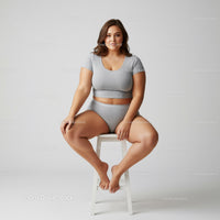 Confident Young Woman Sitting on Stool in Casual Grey Outfit
