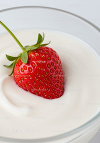 Fresh strawberry gently placed on creamy yogurt swirl