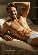 Smiling man relaxing shirtless on bed in natural light