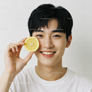 Young Man Smiling Holding Lemon Slice in Studio Portrait