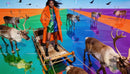 Fashion model standing on sleigh with reindeer in vivid colors