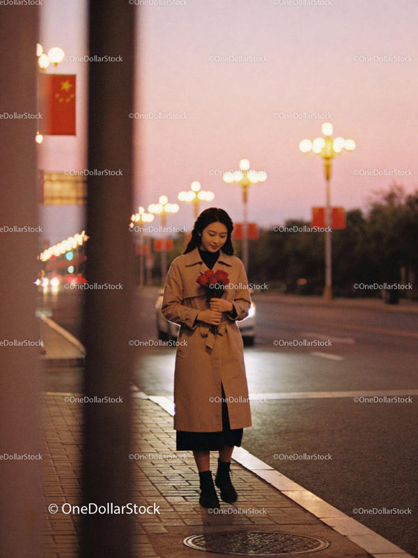 Young woman walking at dusk with roses in city street