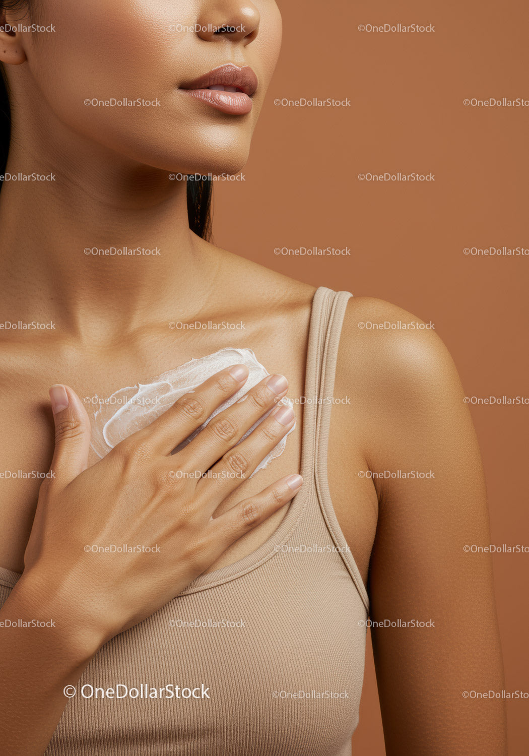 Zbliżenie kobiety nakładającej krem nawilżający na dekolt na tle nude