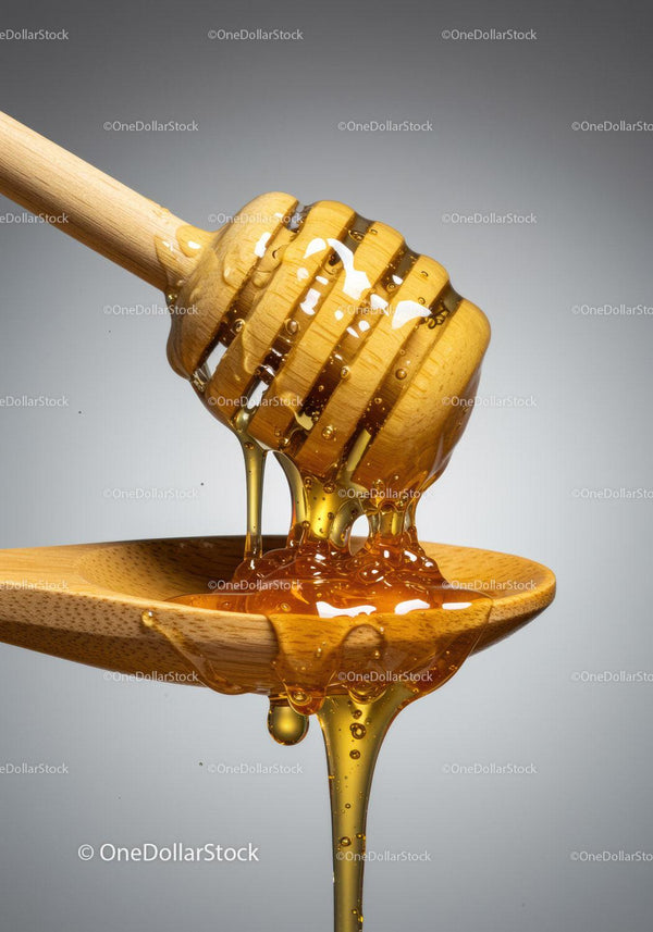 Golden honey dripping from wooden honey dipper