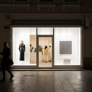 Minimalist fashion boutique window at night with pedestrians