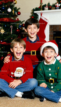 Joyful boys in Christmas sweaters by decorated tree
