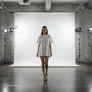 Young woman walking in white dress on studio runway