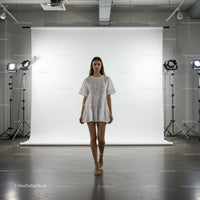 Young woman walking in white dress on studio runway