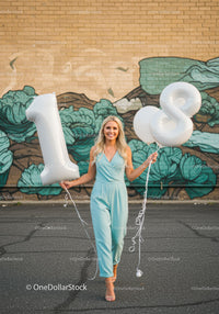 Smiling woman celebrating 18th birthday with balloons
